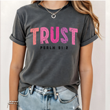 A 3x3 grid showing nine women modeling the same dark gray graphic T-shirt with different colorful text and design prints. The shirts feature phrases such as 'CHOSEN', 'TRUST', 'HIS NAVY IS BETTER', 'BIBLE PLANS HAVE TO BE RIGHT', 'PSALM 23 SHEEPHERD', and others with religious-themed graphics.
