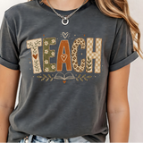 A 3x3 grid showing nine different colorful graphic t-shirts worn by a model. The shirts feature various teacher-themed designs including an apple with the word 'teach', a blue daisy pattern, a rainbow smiley face saying 'BELIEVE SUCCESSION MAKES A DIFFERENCE', a pink heart and book design, a pink and blue 'TEACH A MIDNIGHT' graphic, a rainbow lightning bolt, a patriotic 'TEACHER' design, the word 'teach' in pink script, and a gold glitter-style 'TEACH' graphic.