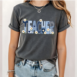 A 3x3 grid showing nine different colorful graphic t-shirts worn by a model. The shirts feature various teacher-themed designs including an apple with the word 'teach', a blue daisy pattern, a rainbow smiley face saying 'BELIEVE SUCCESSION MAKES A DIFFERENCE', a pink heart and book design, a pink and blue 'TEACH A MIDNIGHT' graphic, a rainbow lightning bolt, a patriotic 'TEACHER' design, the word 'teach' in pink script, and a gold glitter-style 'TEACH' graphic.