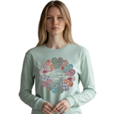 Woman wearing a light green long-sleeve shirt with floral design and text.